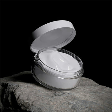 White cream in an open jar on a rock.