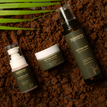 Three skincare bottles on dark soil