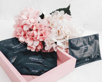Skincare packages and flowers in a pink tray.