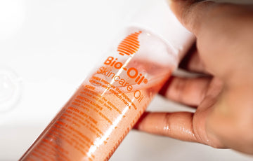 Hand holding a bottle of bio-oil skincare oil.