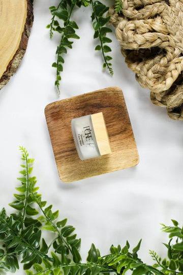 A small jar of cream on a wooden square.