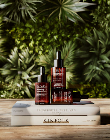 Three bottles of dr. k rosehip oil on stacked books.